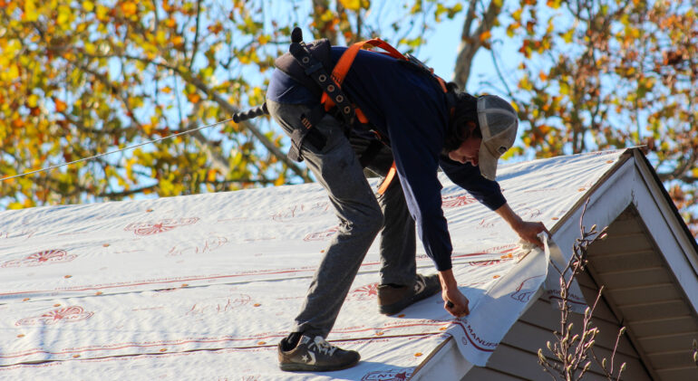 Roofer placing materials on steep roof